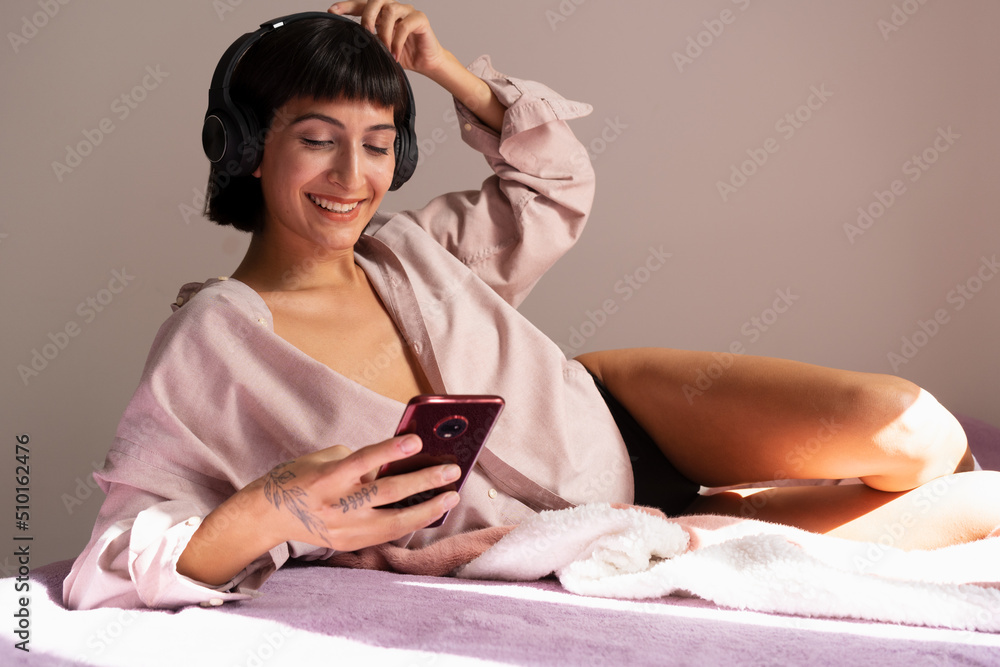 Woman smiling with earphones on her head in the bedroom Woman smiling with earphones on her head in the bedroom