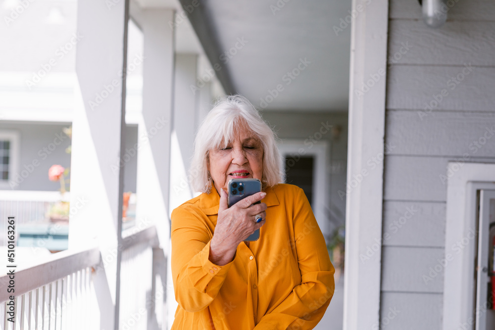 Modern senior woman using mobile phone outside residence Modern senior woman using mobile phone outside residence