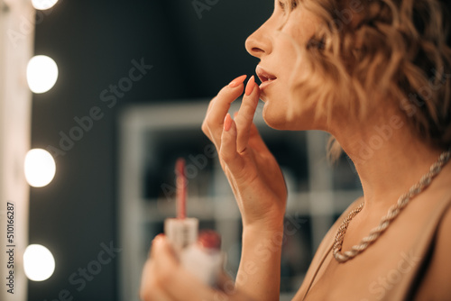 Woman ajusting lipstick with fingers photo