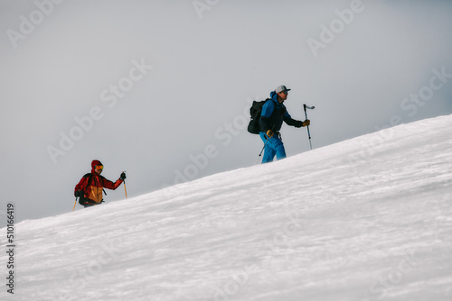Two Skiers Climbing Mountain in Windy Conditions photo