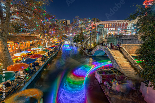 Christmas Lights illuminated San Antonio downtown River Walk with Restaurants on side and boats on the river in Texas, USA