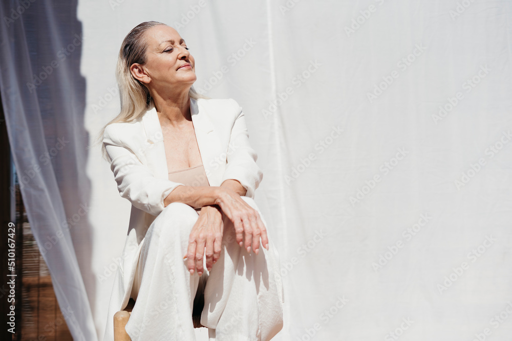 Serene elegant senior woman enjoying the sun at terrace Serene elegant senior woman enjoying the sun at terrace