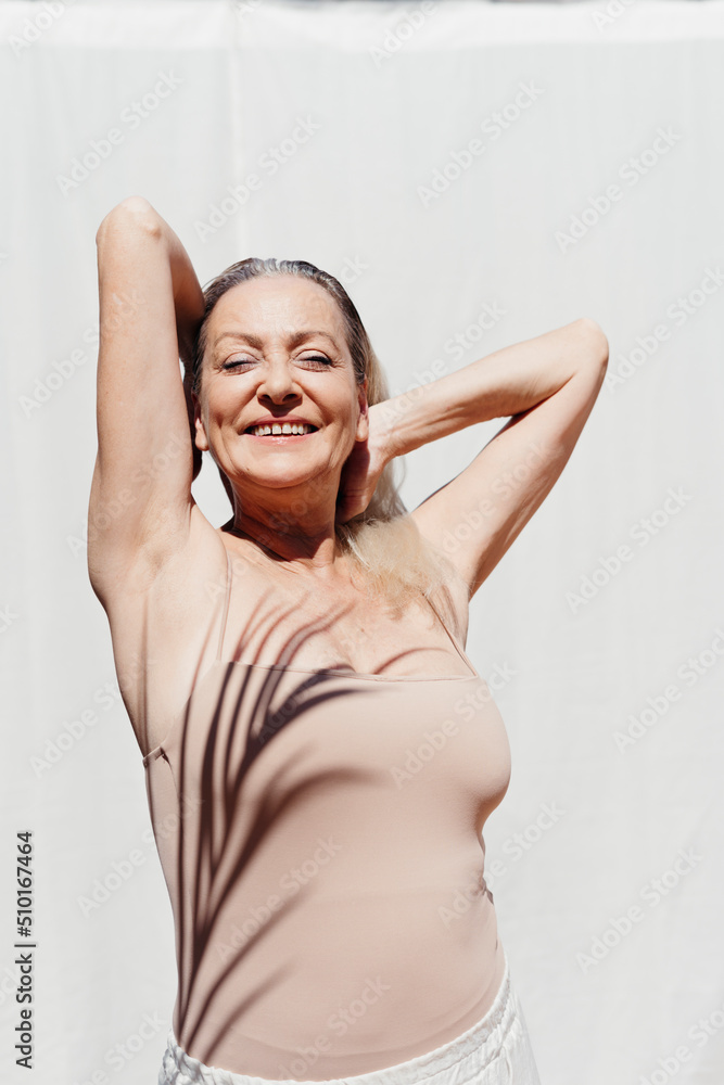 Delighted mature woman shaded by palm leaf outdoors