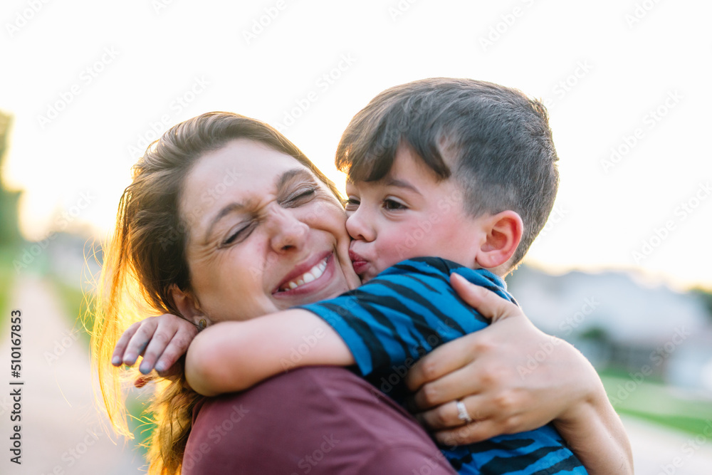 Child kises and wraps arms around mom Child kises and wraps arms around mom