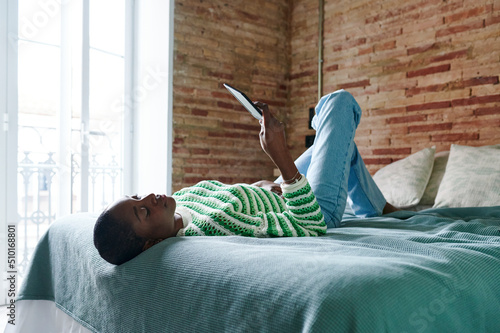 Young woman lying on her bed with an e-reader photo