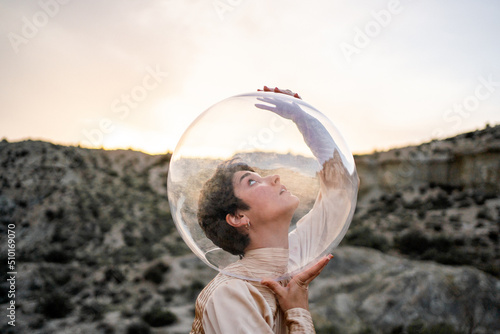 Art Portrait Of A Girl With Dress And Bubble Helmet In The Desert.