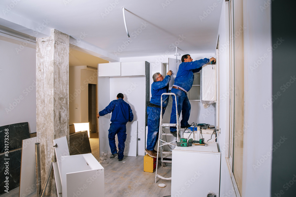 Team of workers assembling kitchen furniture Team of workers assembling kitchen furniture