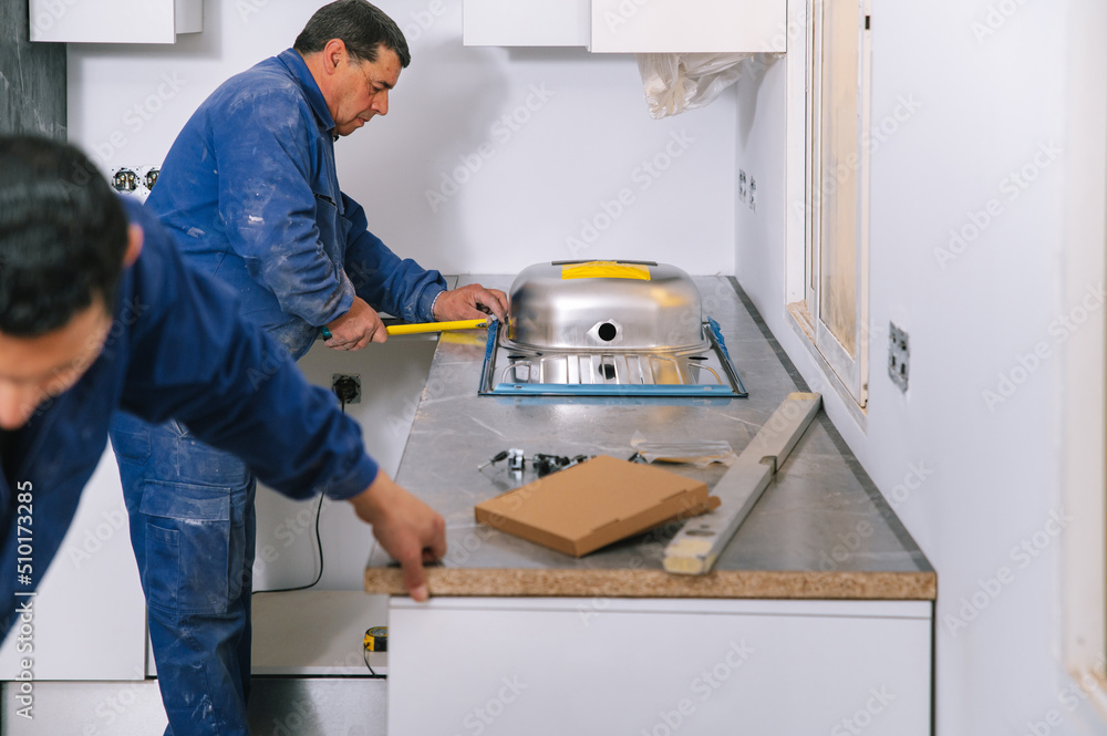 Crop workers installing sink in kitchen Crop workers installing sink in kitchen
