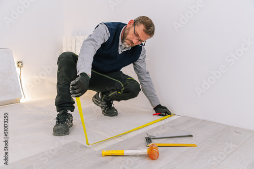 Interior designer measuring floor planks photo