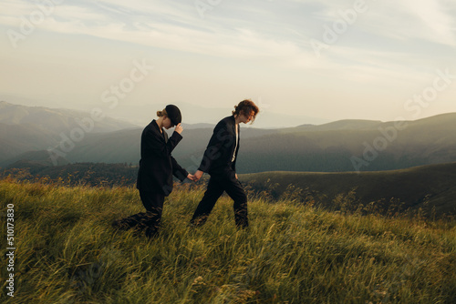 Stylish couple in black suits on a walk among mountain landscapes