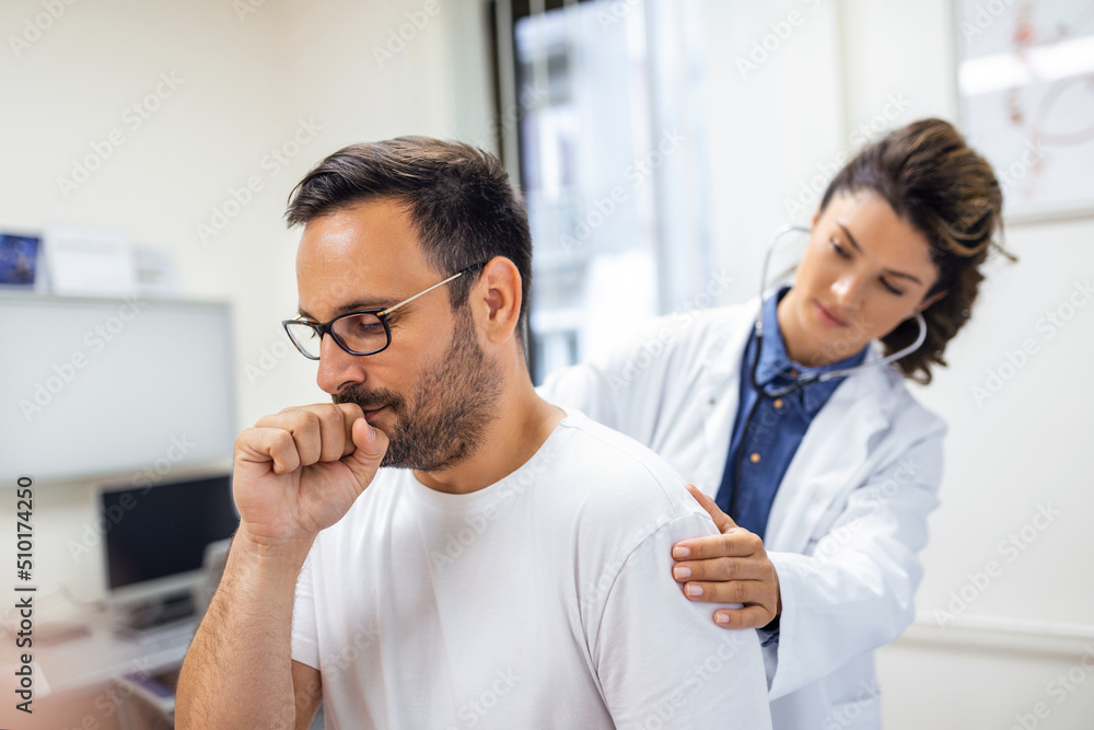 Obraz premium A female doctor at the clinic performs auscultation of the lungs of a patient with symptoms of coronavirus or pneumonia.