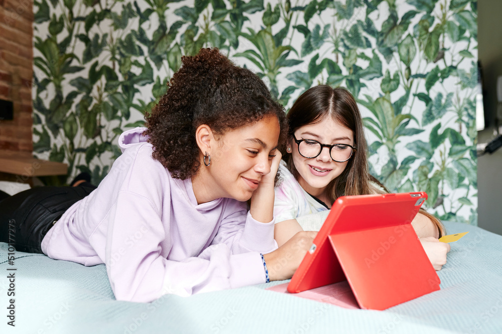 Teens lying on a bed and watching something on a tablet Teens lying on a bed and watching something on a tablet