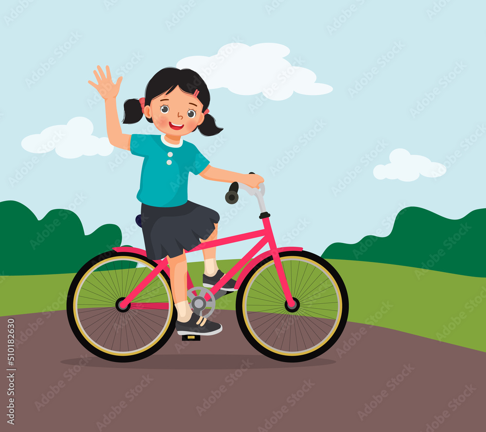 happy little girl riding a bike having fun in the park on sunny day waving hand happy little girl riding a bike having fun in the park on sunny day waving hand