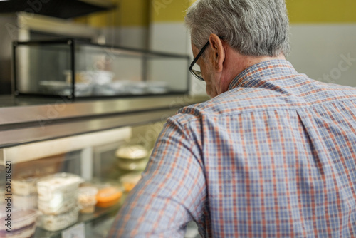 Senior man looking at food products at a store counter photo