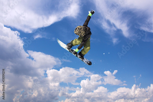 Snowboarder in action jumping against blue sky