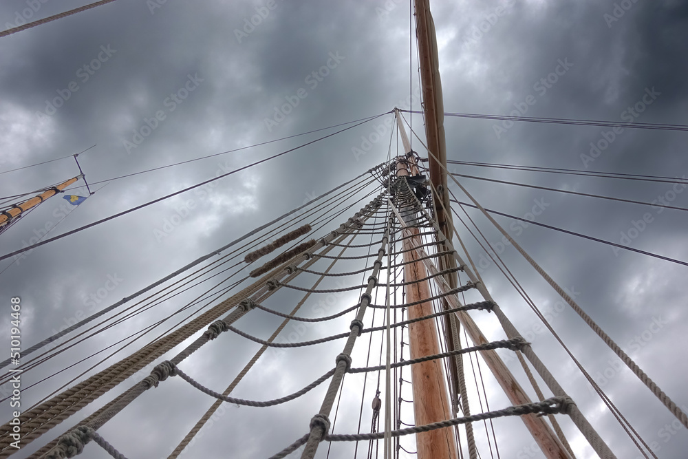 Fototapeta premium Storm clouds forming above the mast and rigging of a sailboat as a sign of bad news 