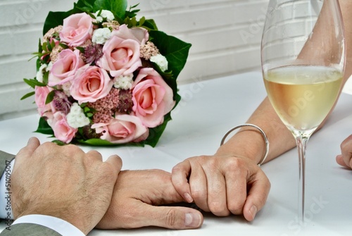 Nach der Hochzeit Händchen halten mit Brautstrauß und Champagner 