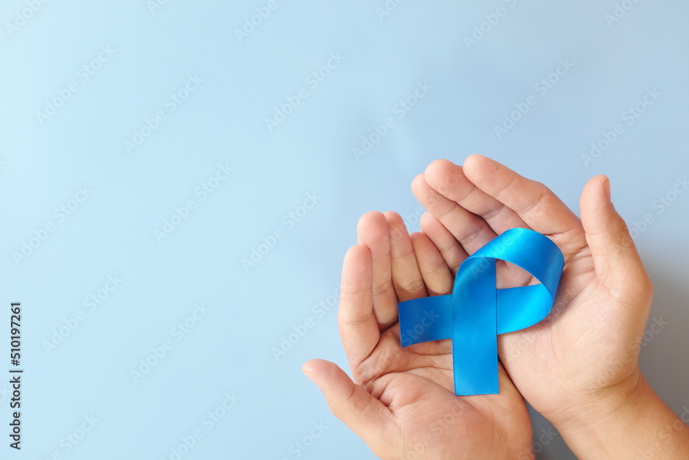 Top view of hands holding blue awareness ribbon. Prostate cancer, colon and colorectal cancer, peace, alopecia and arthritis care concept.