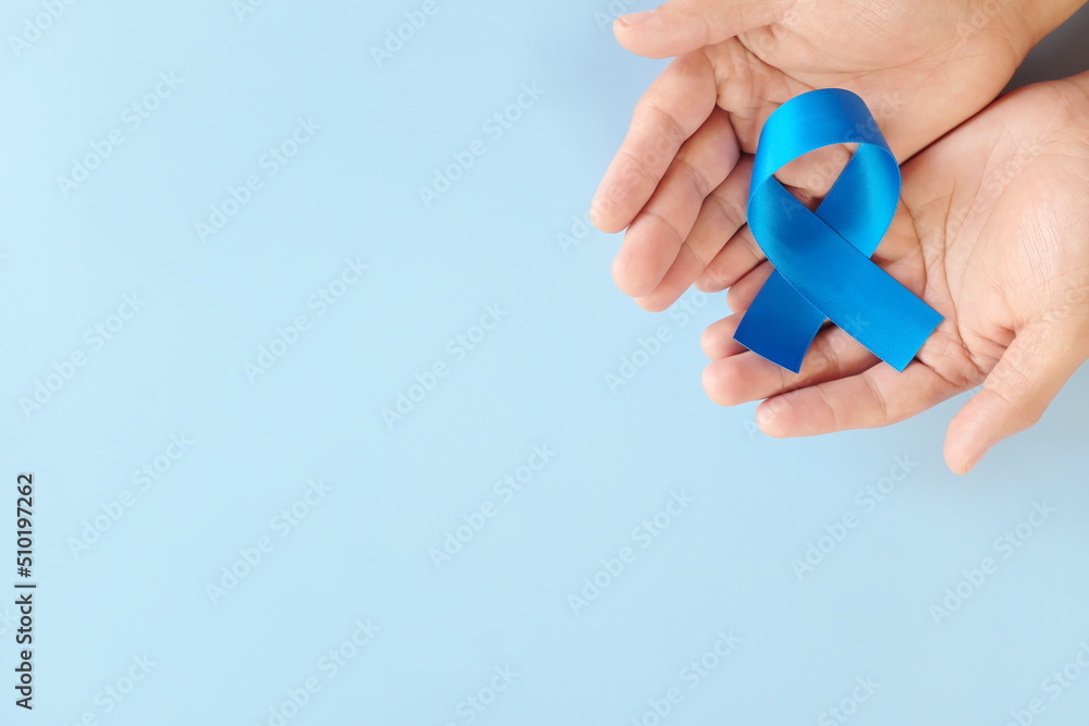 Top view of hands holding blue awareness ribbon. Prostate cancer, colon and colorectal cancer, peace, alopecia and arthritis care concept.