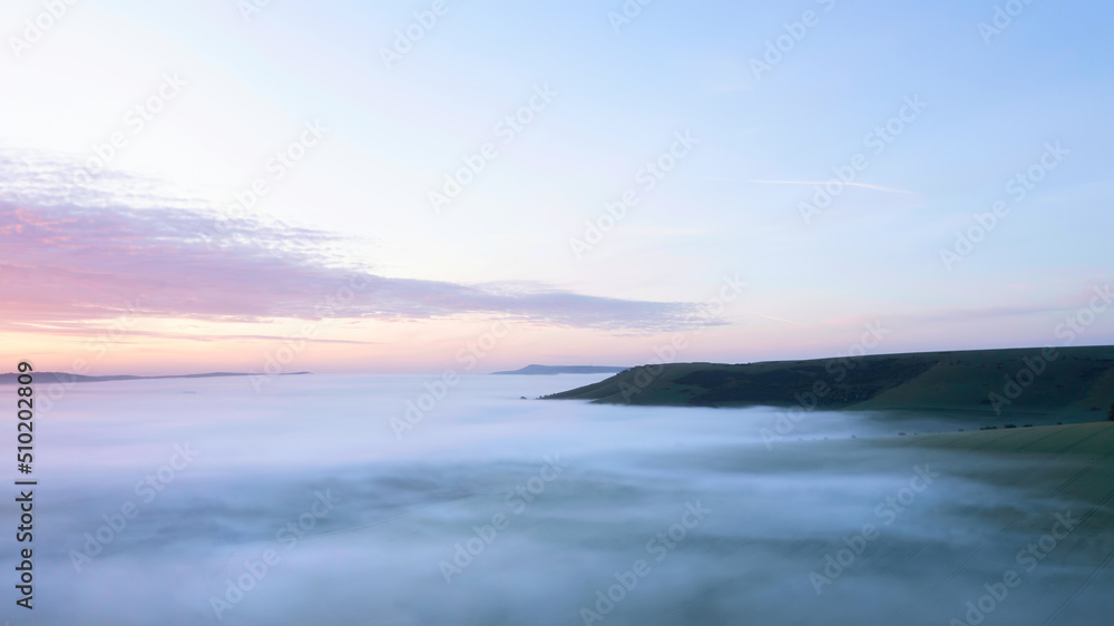 Majestic drone landscape image of sea of fog rolling across South Downs English countryside during Spring sunrise