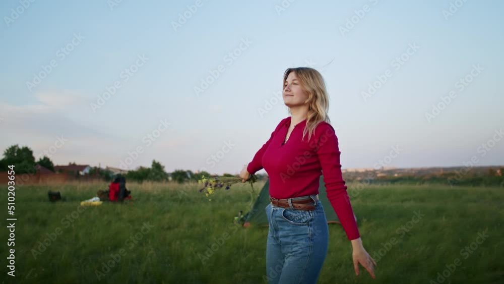 a young woman happily rests on the mountain hills during sunset, for rest after a hike. rest of one person in nature, in the mountains.