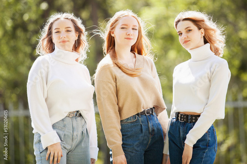 a company of young attractive girls in jeans and sweaters on the street