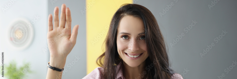 Beautiful young woman lift hand as hello gesture sit in living room Beautiful young woman lift hand as hello gesture sit in living room