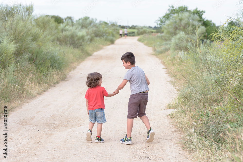 Two Caucasian brothers stroll through the countryside approaching storm clouds on a summer evening. Two Caucasian brothers stroll through the countryside approaching storm clouds on a summer evening.