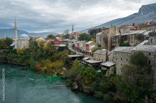 Beautiful Mostar View on Fall with Islamic Mosques. Medieval Stone Houses, Souvenir Shops, Neretva River in Day. Mountains Background. Bosnia and Herzegovina.