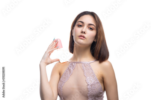 A beautiful sexy lady in an elegant nude bodysuit holds a bottle in her hands. Fashion beauty portrait of fashion model girl on isolated white background.