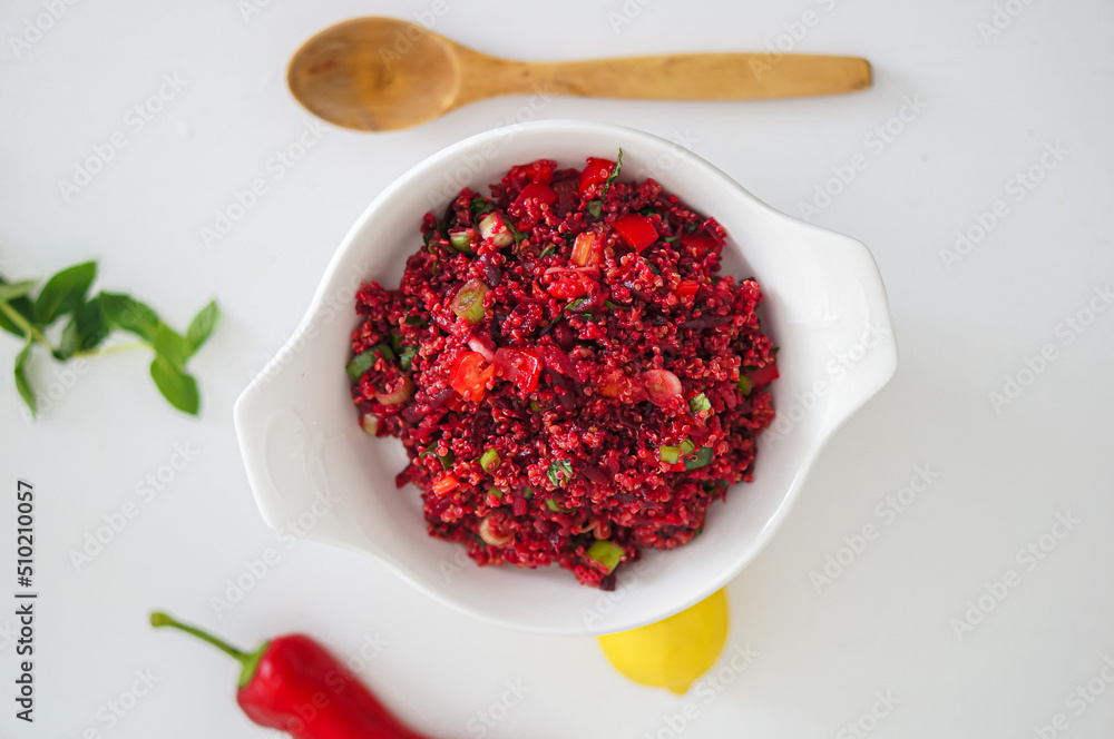 Top view of Selective focus beetroot quinoa salad with wooden spoon, fresh mint, lemon and red pepper on white table. Top view of Selective focus beetroot quinoa salad with wooden spoon, fresh mint, lemon and red pepper on white table.