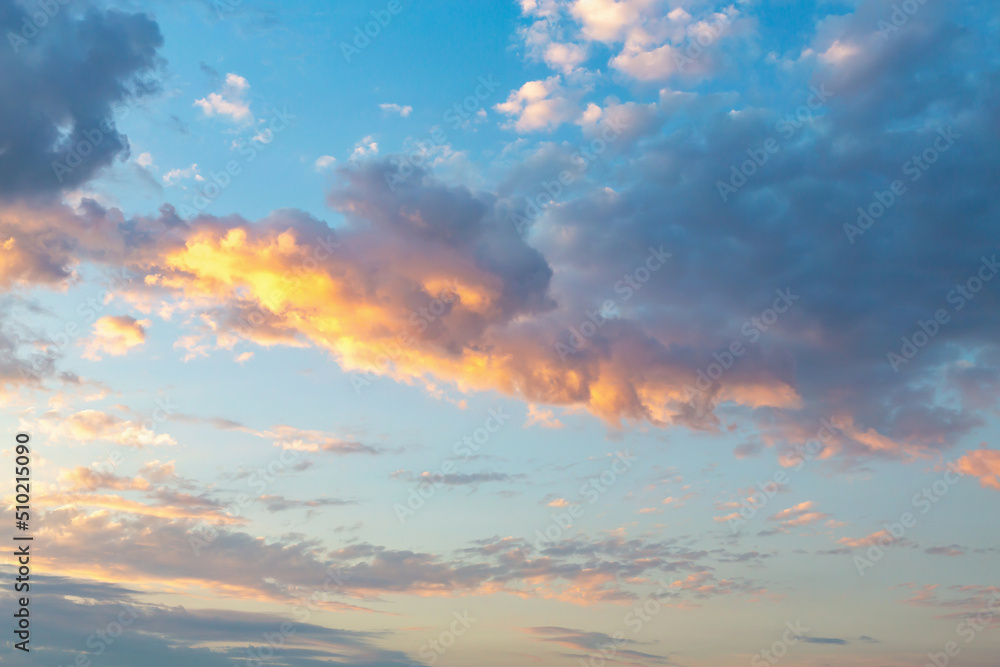 Beautiful fluffy clouds painted in bright painterly colors at sunset. Multicolor background or wallpaper