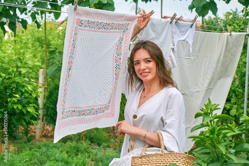 A young woman hangs out laundry outdoors.