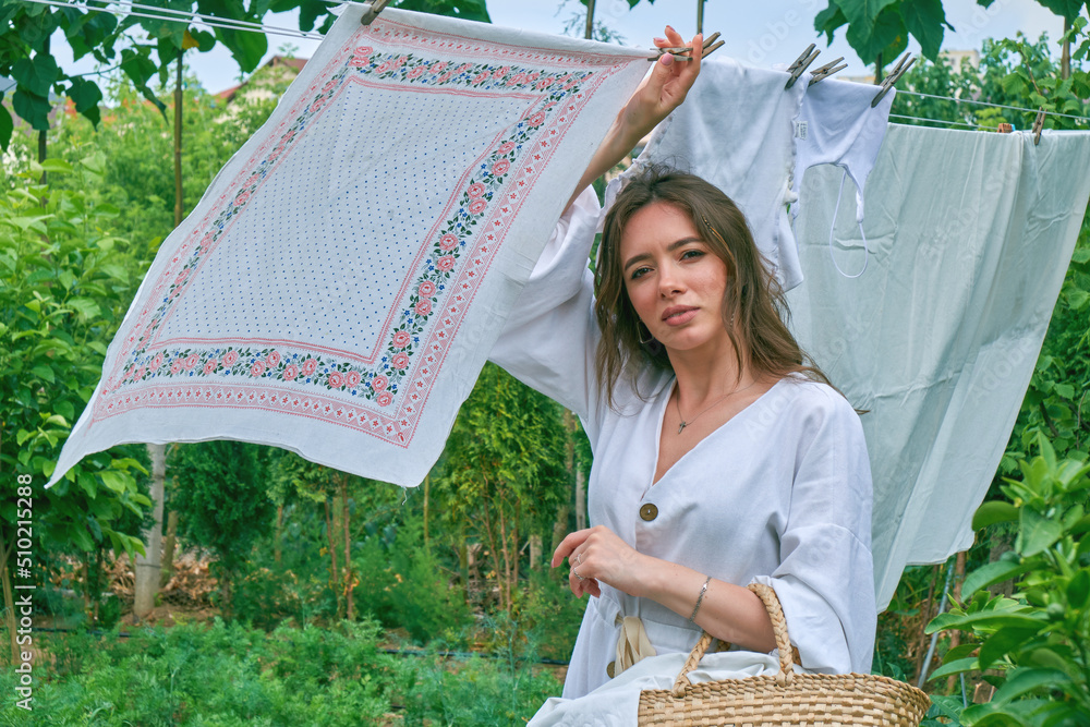 A young woman hangs out laundry outdoors.