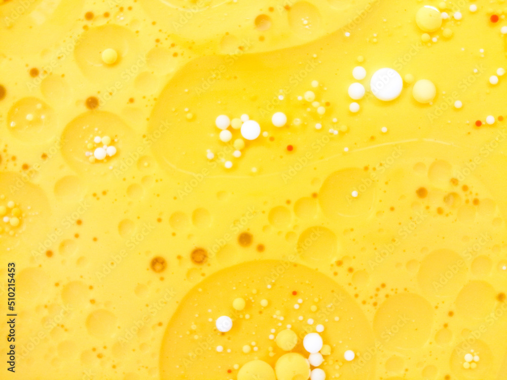 Abstract yellow, white water bubbles background. .Full frame of the textures formed by the bubbles and drops of oil mixed food coloring with milk in the shape of circle floating on water