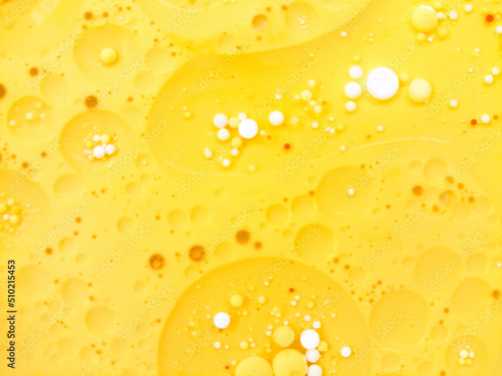 Abstract yellow, white water bubbles background. .Full frame of the textures formed by the bubbles and drops of oil mixed food coloring with milk in the shape of circle floating on water Abstract yellow, white water bubbles background. .Full frame of the textures formed by the bubbles and drops of oil mixed food coloring with milk in the shape of circle floating on water