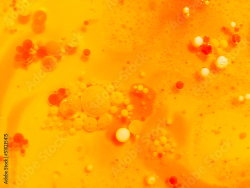 Abstract yellow, orange water bubbles background. .Full frame of the textures formed by the bubbles and drops of oil mixed food coloring with milk in the shape of circle floating on water