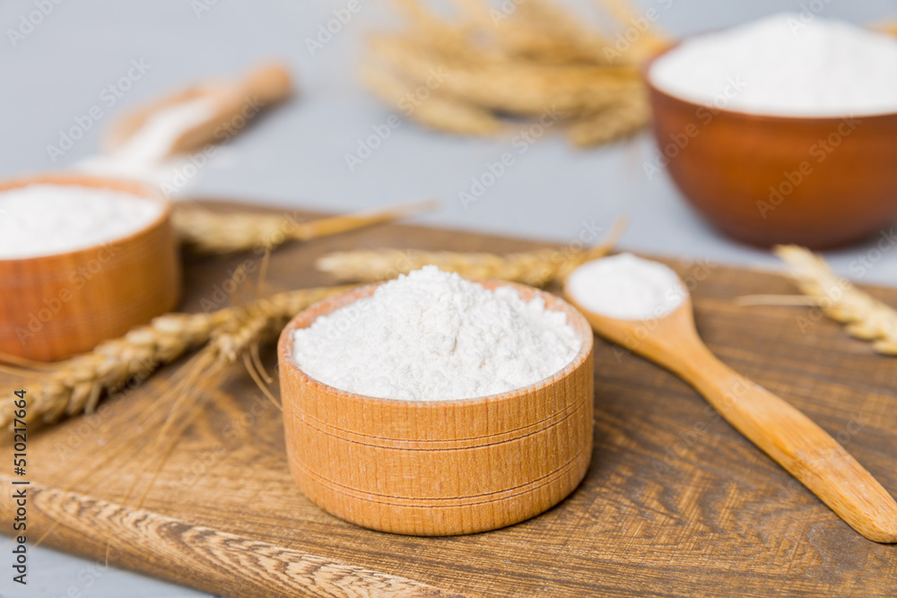 Flat lay of Wheat flour in wooden bowl with wheat spikelets on colored background. world wheat crisis Flat lay of Wheat flour in wooden bowl with wheat spikelets on colored background. world wheat crisis