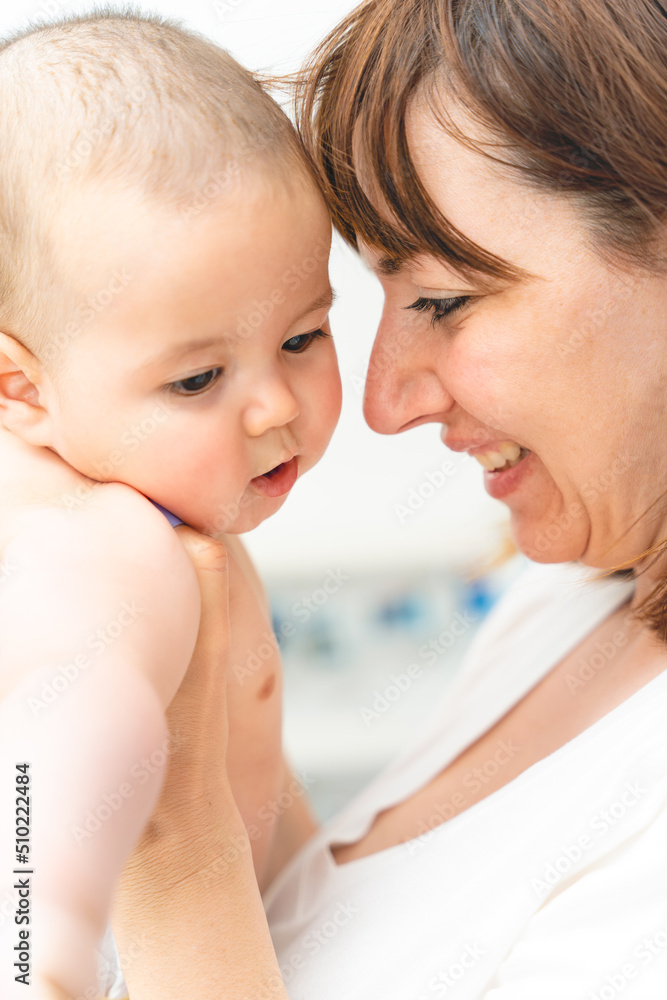Young mother hugging her little son, sitting near the window and smiling. Young mother hugging her little son, sitting near the window and smiling.