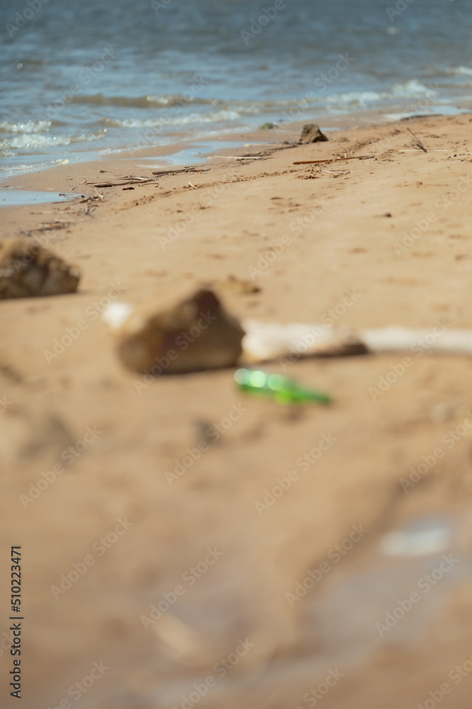 Bear glass bottle on the sand. Garbage on the dirty beach. Selective focus Bear glass bottle on the sand. Garbage on the dirty beach. Selective focus