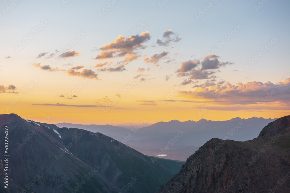 Atmospheric alpine landscape with large mountains in orange dawn sky. Colorful top view to high mountain range under cloudy sky in sunset colors. Awesome mountain sunset scenery at very high altitude. Atmospheric alpine landscape with large mountains in orange dawn sky. Colorful top view to high mountain range under cloudy sky in sunset colors. Awesome mountain sunset scenery at very high altitude.