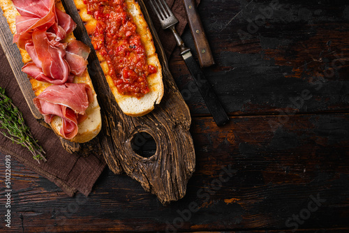 Spanish cured serrano ham with olive oil and toasted bread, on old dark  wooden table background, top view flat lay, with copy space for text photo