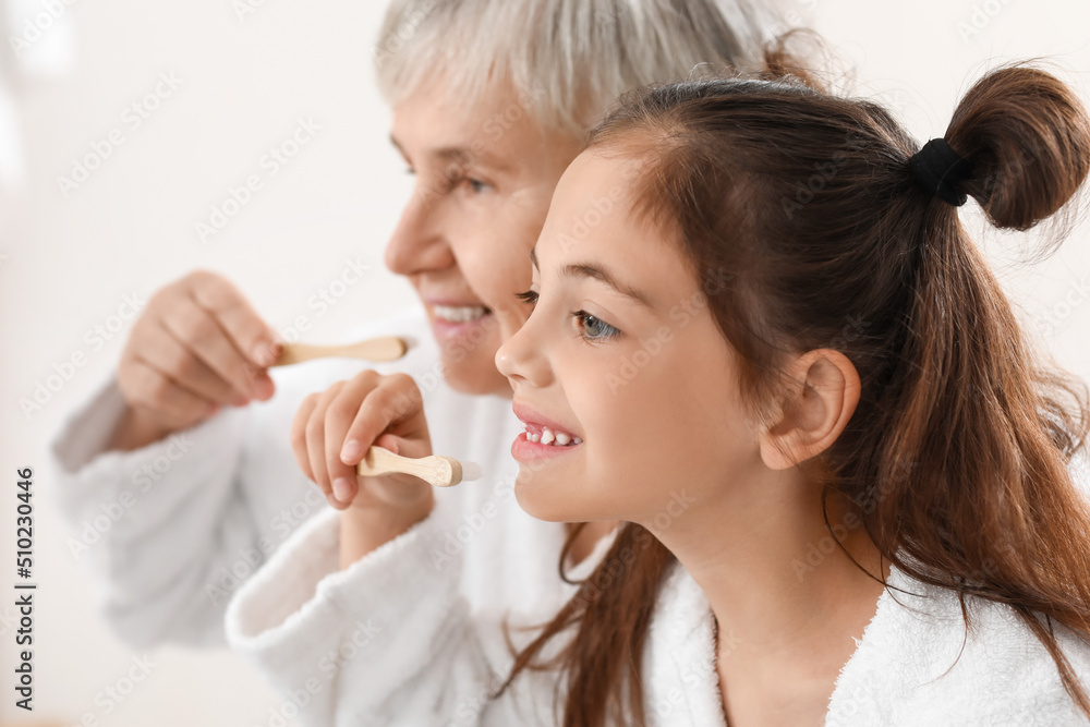 Little girl and her grandma brushing teeth in bathroom, closeup Little girl and her grandma brushing teeth in bathroom, closeup