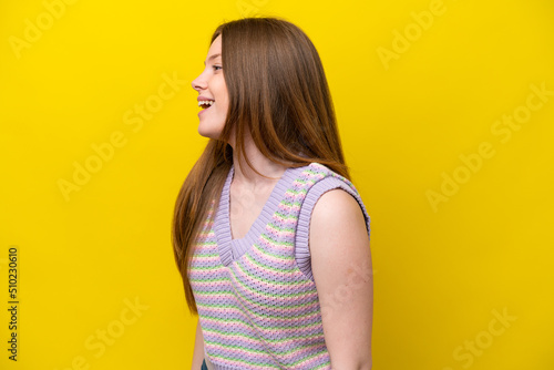 Young caucasian woman isolated on yellow background laughing in lateral position