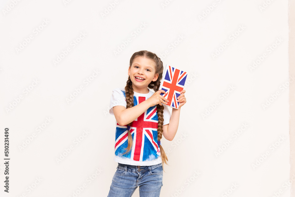 Naklejka premium A child with the flag of Great Britain on his football holds a book on the English language. Learning English for children,