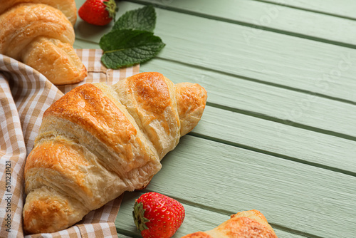 Delicious croissants on green wooden background, closeup