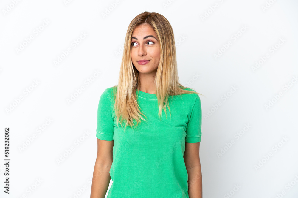Blonde Uruguayan girl isolated on white background making doubts gesture looking side Blonde Uruguayan girl isolated on white background making doubts gesture looking side