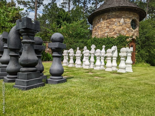Low angle view of an out doors chess set. Played on green grass with large chess pieces.