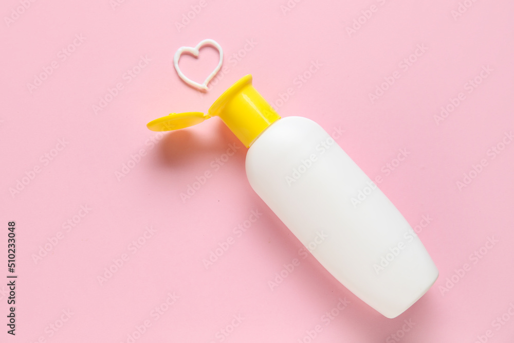Bottle of sunscreen and heart made of cream on pink background Bottle of sunscreen and heart made of cream on pink background