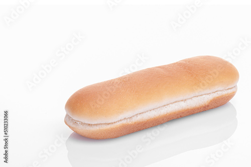 a hot dog bun lies diagonally on a white background